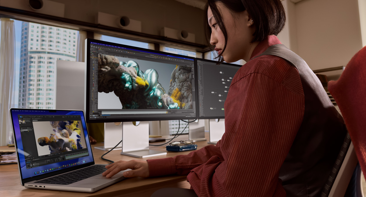 Inimene töötab kontoris MacBooki sülearvutiga, mis on ühendatud Thunderbolt 5 liidese kaudu Studio Display XDR-iga