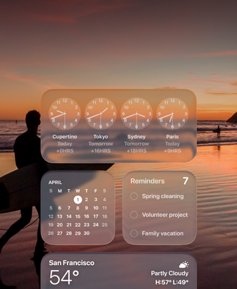 Clock, Calendar, Reminders un Weather vidžeti Liquid Glass dizainā uz macOS Tahoe ekrāna, un tiem fonā ir kadrs, kurā sērfotājs pastaigājas pa pludmali saulrietā
