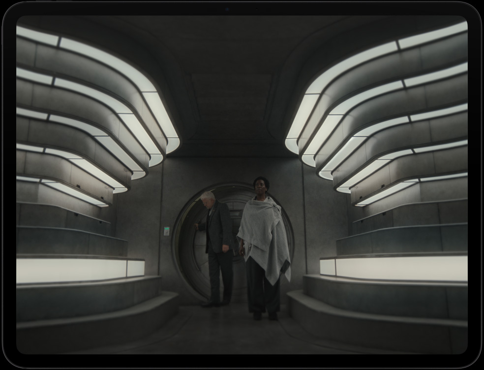 iPad Pro, display with image of 2 people entering a futuristic interior in the Apple TV series Silo.