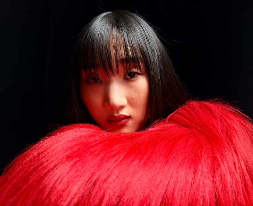 Primo piano di una donna che indossa un top rosso vivace a piume, per mostrare l’altissima risoluzione fotografica di iPhone 17 Pro